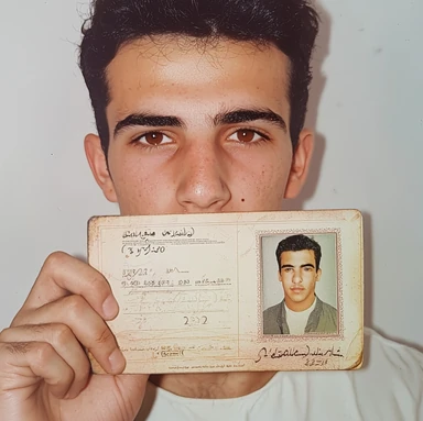 Photo on file: a young man with dark hair holding up his ID document