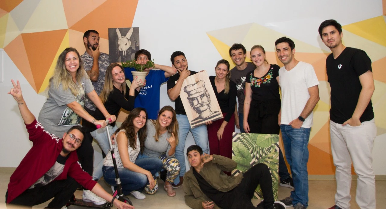 The early Oitchau team posing together in the office. Bruno stands in the middle, in a black T-shirt, holding a wooden painting.